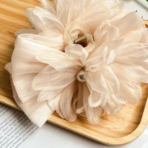 Dettaglio della grande molletta per capelli a fiore in tessuto beige con perla