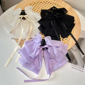 Detailed view of three oversized chiffon bow hair clips in white, black, and lavender