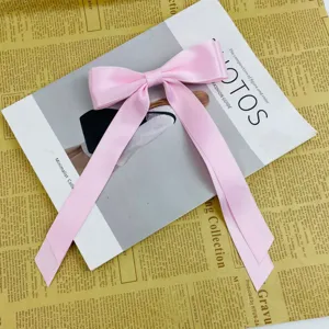 Detailed view of a sweet pink ribbon bow hair clip on a vintage newspaper background
