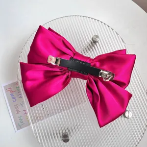 Back view detail of a fuchsia satin bow hair clip with durable metal automatic barrette.