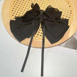 Detailed macro view of an elegant black textured chiffon bow hair claw clip on rattan.