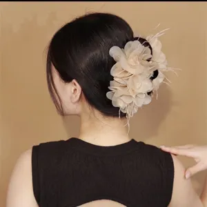 Elegante beige stoffen bloem en veer haarklem gestyled op het achterhoofd van model.