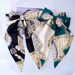 Detail of two elegant oversized bow hair clips with chain print and long ribbons
