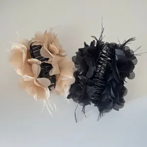 Detail van elegante haarklemmen met stoffen bloemen en veren in beige en zwart