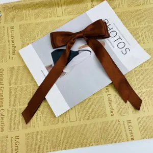 Close-up of large brown satin ribbon bow hair clip on vintage newspaper background