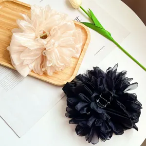Dettaglio di due grandi mollette per capelli con fiori in chiffon, crema e nero.