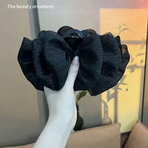 Close-up detail of large black glittery bubble bow hair claw clip with elegant texture