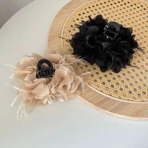 Detail van handgemaakte stoffen bloem haarklemmen met veren in zwart en beige kleuren