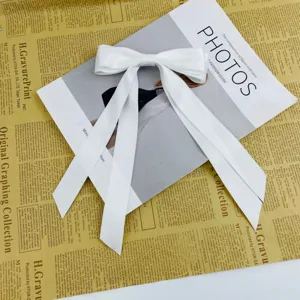 Close-up detail of a large white satin ribbon bow hair clip on vintage newspaper pages