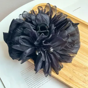 Dettaglio di una grande pinza per capelli a fiore in tessuto nero con eleganti petali 3D