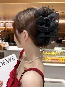 Close-up detail of an elegant black mesh bubble hair claw clip with feather accents