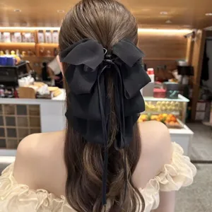 Elegant black chiffon bow hair clip shown on back of head in lifestyle cafe setting
