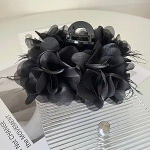 Gedetailleerde weergave van een elegante zwarte stoffen bloem haarklem met verendetails
