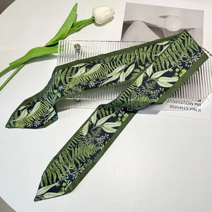 Detailed close-up showing the green forest leaf pattern on a silk ribbon hairband