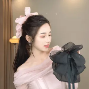 Detailed view of an elegant chiffon bow hair claw clip shown on a model for French style