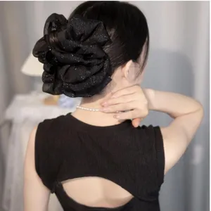 Detail view of large black glittery bubble cloud bow hair clip on model's bun