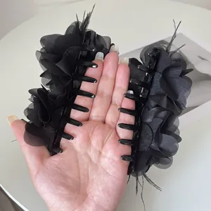 Gedetailleerd overzicht van hand met zwarte stoffen bloemen haarklemmen met veren