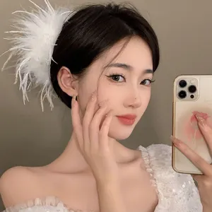 Detail view of a large white ostrich feather hair claw clip worn on a model's head