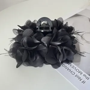 Detail van elegante zwarte stoffen bloem haarklem met verfijnde veren accenten
