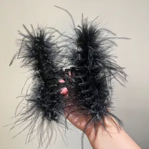 Macro detail of elegant large black ostrich feather hair claw clip being held in hand