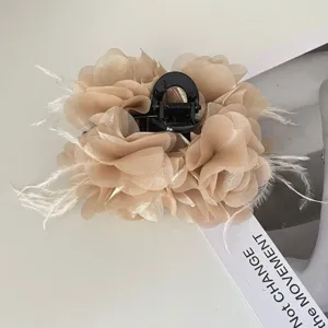 Detail van een elegante haarklem met stoffen bloemen en delicate verenaccenten