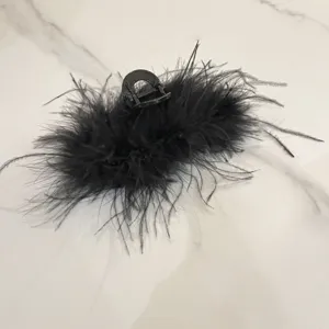 Close-up detail showing the fluffy texture of a black ostrich feather hair claw clip.