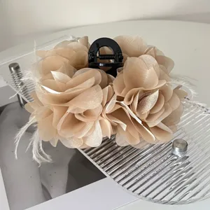 Detailopname van de elegante champagnekleurige stoffen bloem en veren shark haarklem