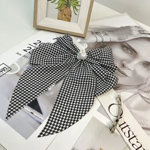 Detail of vintage houndstooth bow hair clip with elegant pearl embellishment for women.
