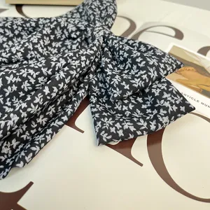 Gros plan sur un tissu noir avec imprimé floral blanc pour un grand nœud barrette