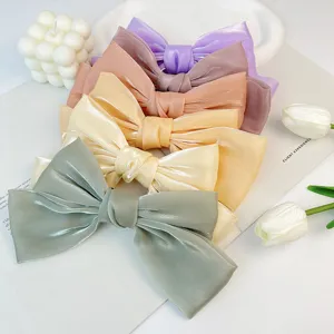 Detail of elegant shiny silk bow hair clips in five soft pastel colors