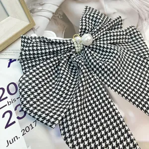 Close-up detail of a retro black and white houndstooth bow hair clip with pearls
