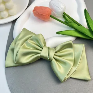 Detail view of elegant light green satin bow hair clip with a smooth glossy texture
