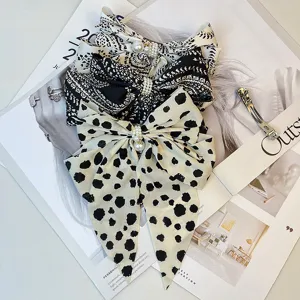 Detailed view of three large satin bow hair clips featuring pearl accents and vintage patterns.