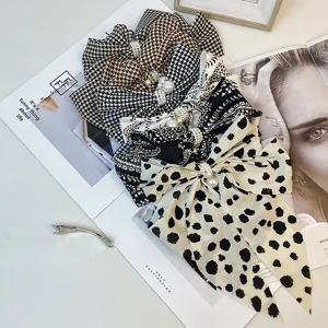 Close-up detail of vintage houndstooth and floral satin bow hair clips with pearl accents