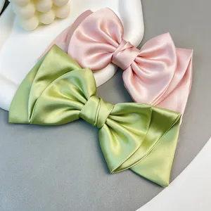 Detailed view of elegant satin bow hair clips in pink and green with a premium finish