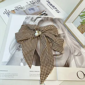 Close-up of a vintage houndstooth bow hair clip with elegant pearl details and texture
