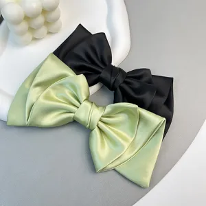 Detail view of black and light green satin bow hair clips on a decorative tray