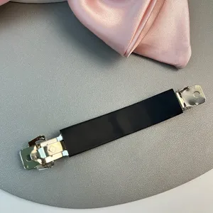 Close-up of a matte black non-marking hair clip with silver metal ends on gray background
