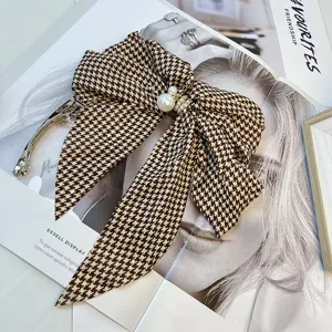 Close-up of vintage houndstooth pattern bow hair clip with elegant pearl detail.