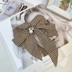 Close-up detail of a vintage houndstooth bow hair clip featuring elegant pearl accents