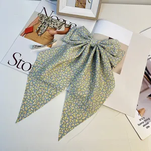 Gros plan d'une pince à cheveux avec nœud floral bleu et élégants longs rubans