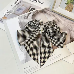 Detail view of a vintage houndstooth pattern bow hair clip with elegant pearl embellishments