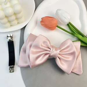Detailed macro view of an elegant pink satin bow hair clip showing smooth fabric texture and shine