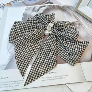 Close-up of a vintage houndstooth bow hair clip with elegant pearl detailing on a magazine