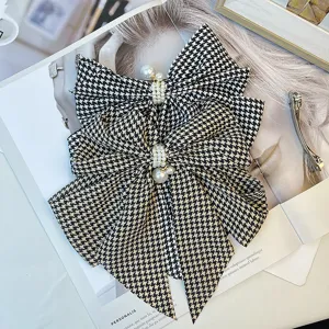 Close-up of retro houndstooth pattern fabric bow hair clip with elegant pearl details