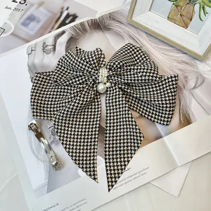 Detail of vintage houndstooth bow hair clip featuring elegant pearl embellishments