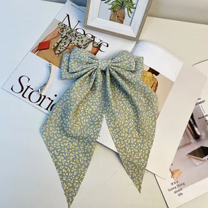 Gros plan détaillé d'une grande pince à cheveux nœud floral bleu avec de longs rubans.
