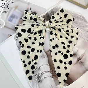 Close-up of a vintage bow hair clip with chic leopard pattern and pearl accents.