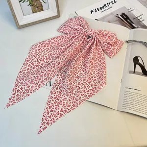 Détail d'un grand nœud de cheveux floral rouge doté de longs rubans élégants et fluides