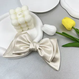 Close-up detailed view of an elegant cream satin bow hair clip with premium texture